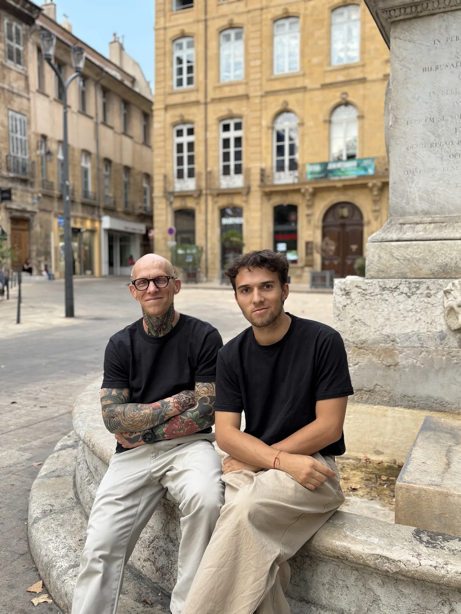 Franck et Quentin assis sur une fontaine, à Aix-en-Provence